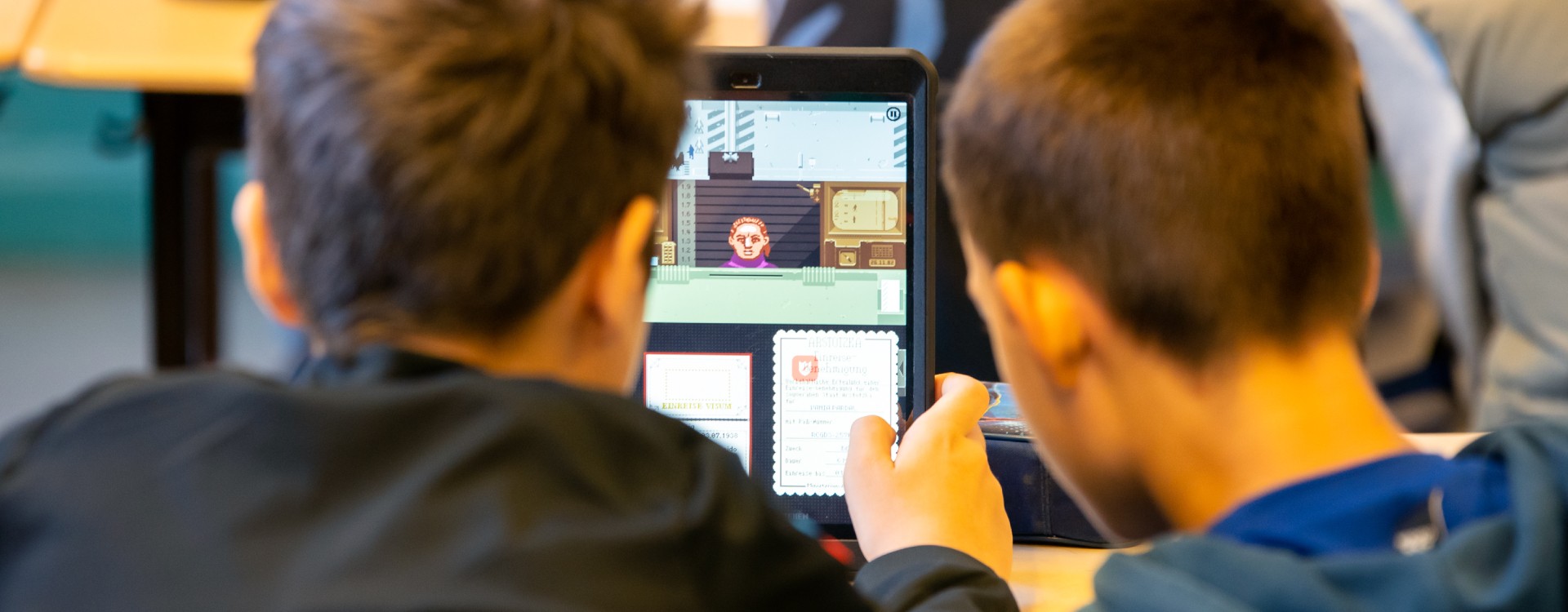 Zwei Schüler spielen gemeinsam an einem Tablet.