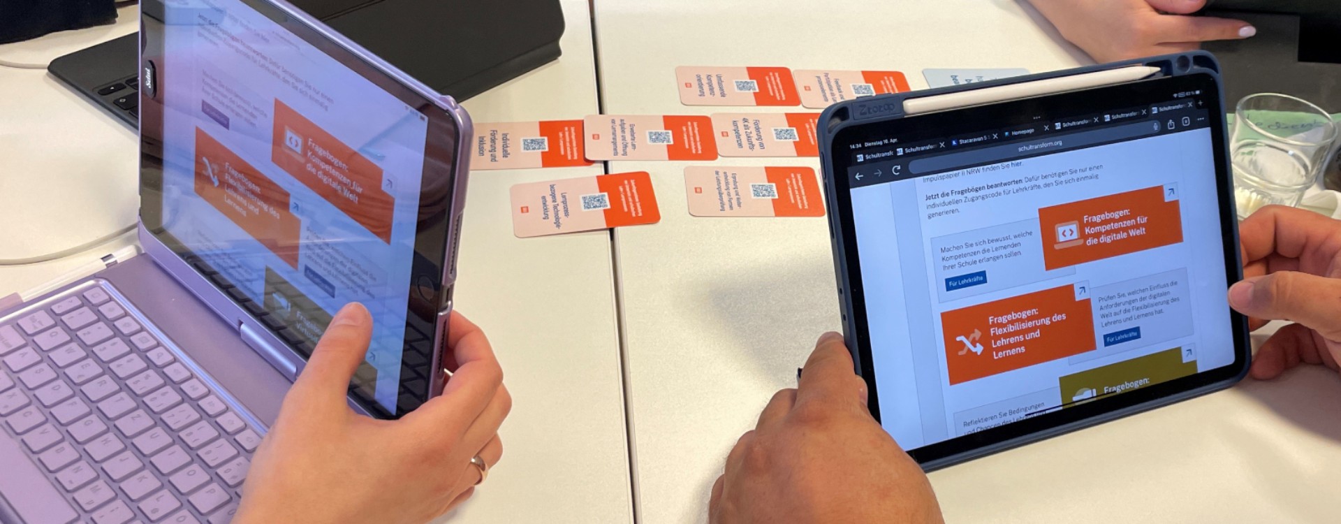 Eine Schulentwicklungsgruppe mit einer im Beratungsgespräch etablierten Kartenaufstellung: die ausgewählten Karten liegen auf dem Tisch und die darauf sichtbaren QR Codes führen zu passenden Fragebögen auf der Onlineplattform.